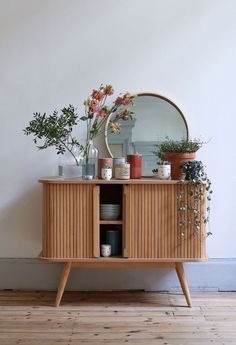 a wooden cabinet with plants and vases on top