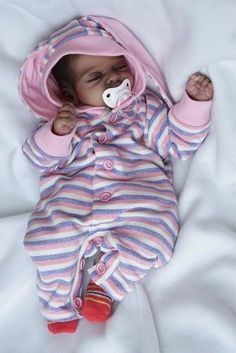 a baby is laying down with a pacifier in it's mouth and wearing a pink striped outfit