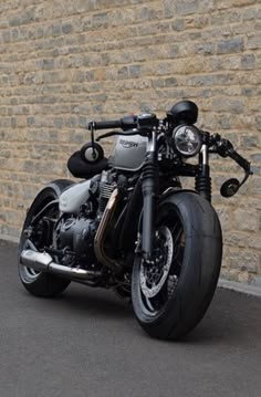 a black motorcycle parked in front of a brick wall