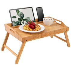 a wooden tray with a plate of food on it and a tablet computer next to it