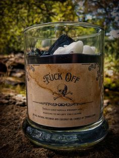 a glass jar filled with lots of rocks and ice cubes sitting on top of a dirt ground