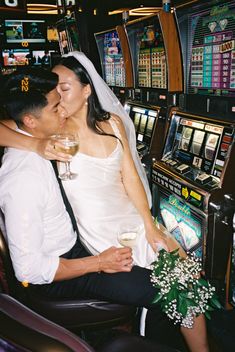 a newly married couple kissing in front of slot machines