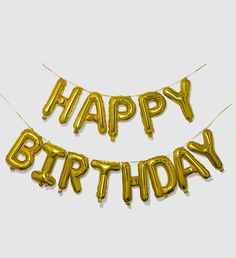 two gold foil balloons with the words happy birthday hanging from it's sides in front of a white background