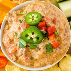 a white bowl filled with dip surrounded by chips and vegetables