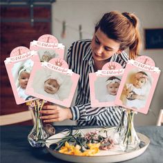 a woman is holding flowers and looking at pictures on a plate with baby's names