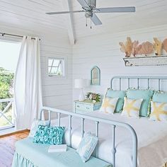 a bedroom with white walls and blue bedding in the center, along with a ceiling fan