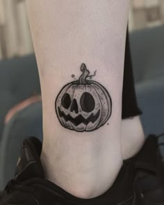 a small black and white pumpkin tattoo on the ankle