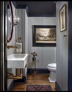 a bathroom with black and white striped walls, wood flooring and a painting on the wall