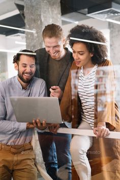 three people looking at a laptop screen in an office building - stock photo - images