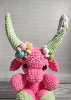 a crocheted pink and green stuffed animal with horns