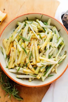 a bowl filled with pasta and vegetables on top of a wooden table