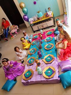 a group of children sitting around a table with plates and cake on it in front of them