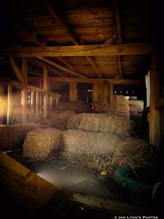 hay bales in an old barn with sunlight coming through the windows