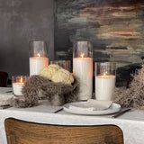 a table topped with candles next to a painting on the wall and plates in front of it