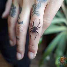 a person with a spider tattoo on their ring finger and the other hand is holding it up