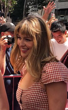 a woman in a red and white checkered dress is holding her hand up to the sky