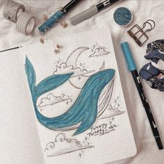 a notebook with a drawing of a whale on it next to some scissors and other items