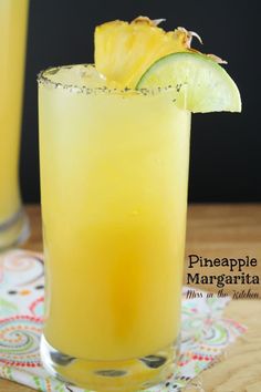 a tall glass filled with yellow liquid and topped with a pineapple garnish