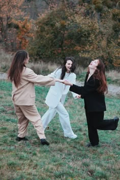 three women are holding hands in the grass