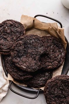 three chocolate cookies sitting on top of a pan next to a cup of milk and spoon