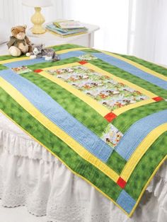 a teddy bear sitting on top of a bed next to a green and yellow quilt