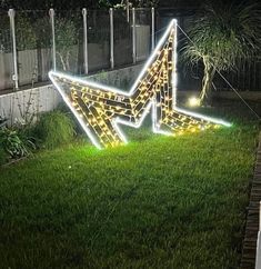 a large lighted arrow in the grass near a fence at night with lights on it