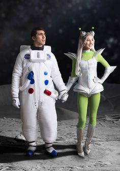 man and woman dressed as astronauts walking on the moon with their hands in each other's pockets