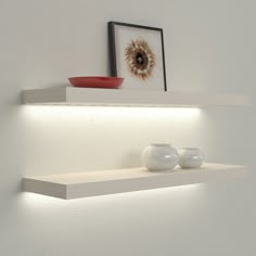 two white vases sitting on top of a shelf next to a framed photograph and an orange bowl