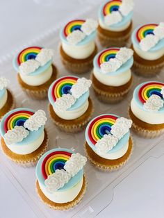 cupcakes with rainbow frosting and white icing on a clear plastic tray