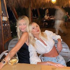 two women sitting at a table with wine glasses