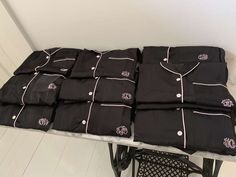 many black shirts are stacked on top of each other at the end of a table