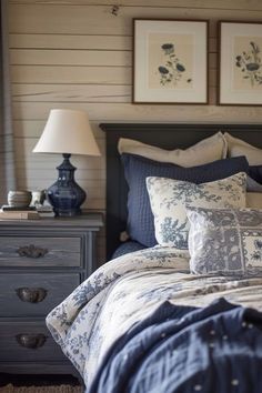 a bed with blue and white linens in a bedroom next to two framed pictures