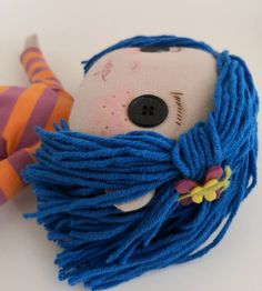 a stuffed animal with blue dreadlocks on it's head and eyes is laying down