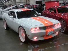 an orange and gray car is parked in a garage with other cars behind it,