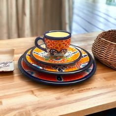 a stack of colorful plates sitting on top of a wooden table next to a wicker basket