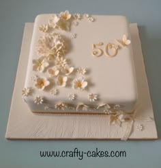 a cake with white frosting and flowers on the top is decorated with gold numbers