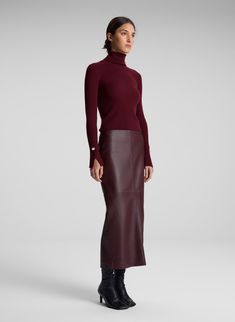 The Jett Top is crafted from stretch merino wool in a burgundy hue. This long-sleeve silhouette features a foldover turtleneck and two sleek slits placed along the sleeves. Shop Tops. Styling Tip: Wear with tailoring for the day and a fluid skirt to transition to evenings. Burgundy On Burgundy Outfit, Leather Skirt Design, Burgundy Tops For Women, Burgundy Sweater Vest Outfit, Casual Winter Outfits Skirt, Brown Leather Maxi Skirt Outfit, Wine Colored Outfits, Long Leather Skirt Outfit Winter, Eggplant Outfit