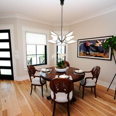 a dinning room table and chairs in front of a window with pictures on the wall