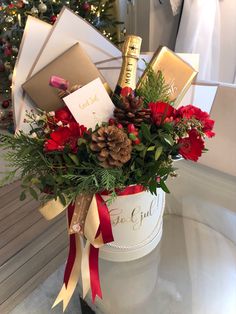 a christmas arrangement in a white bucket with red flowers, pine cones and other holiday decorations