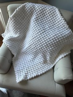 a white crocheted blanket sitting on top of a chair