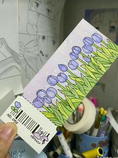 a person holding up a piece of paper with flowers on it in front of a drawing