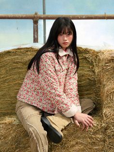 a woman sitting on top of a pile of hay