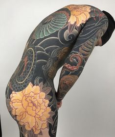 the back of a woman's body with tattoos and flowers on her leggings