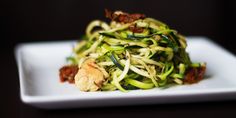 a white plate topped with zucchini noodles and meat