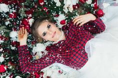 a woman laying on the ground surrounded by red and white flowers with her hands behind her head