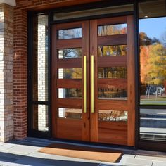 a pair of wooden doors with glass on the front of a brick building in autumn