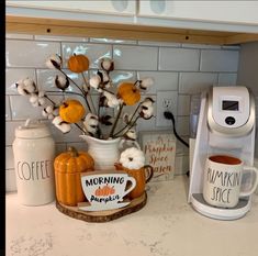 a coffee maker sitting on top of a counter next to a cup filled with pumpkins