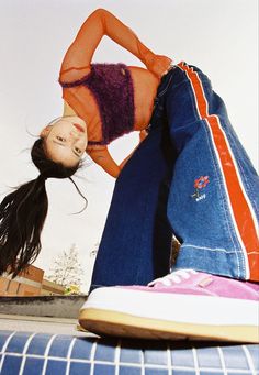 a woman in orange shirt and jeans laying on the ground