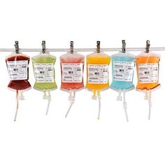 four bottles with different colored liquids hanging from the top on a rack against a white background