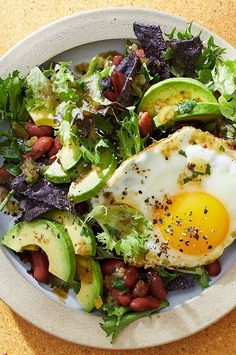 an egg is on top of a salad with beans and avocado